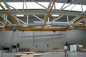 Crane operator controls overhead travelling crane with trolley in production hall in Austria