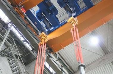 Double-girder travelling crane for sensitive lifting and lowering of the pump elements