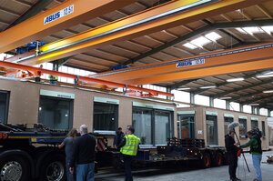 Double-girder traveling cranes working in tandem operation to transport a SmartHouse