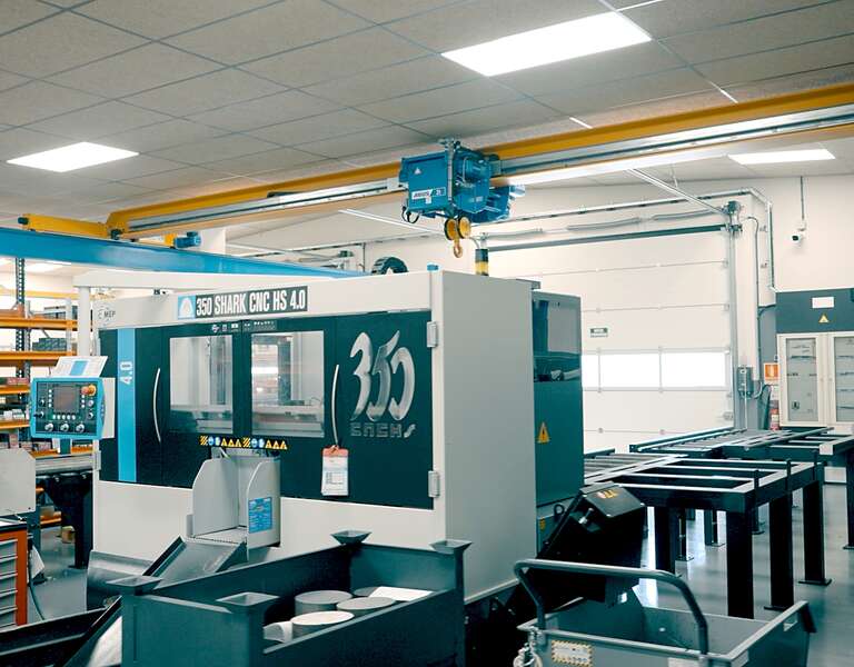 A factory hall with machine tools. An ELV bridge crane with electric wire rope hoist travels on a crane track.