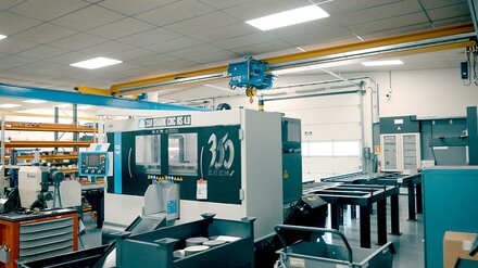 A factory hall with machine tools. An ELV bridge crane with electric wire rope hoist travels on a crane track.