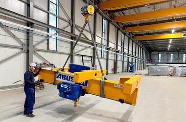 The main girder of a semi-goliath crane is lifted into position for assembly on a wire rope hoist.