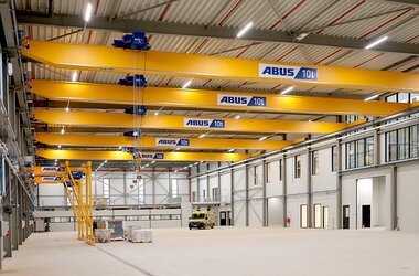 View into a large production hall with five ELK overhead travelling cranes on a common crane track. On the second level, two semi-goliath cranes.