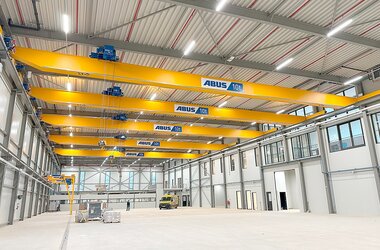 A factory hall with five single-girder overhead travelling cranes on a common track.