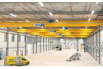 An industrial hall with several overhead travelling cranes on one track, with an ABUS service vehicle in the foreground.