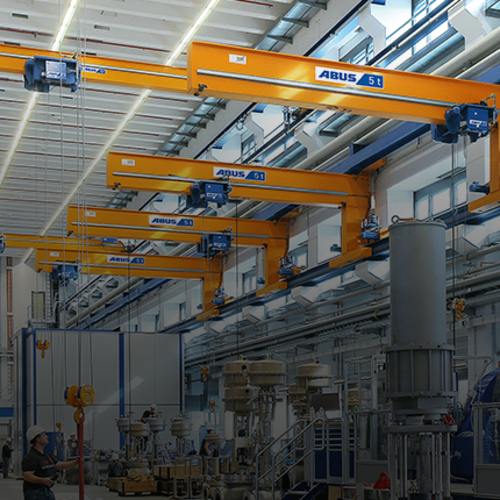 ABUS wall travelling cranes in an industrial hall, with a load capacity of up to 5 tonnes and a span of up to 12 metres, for the efficient servicing of multiple workstations.